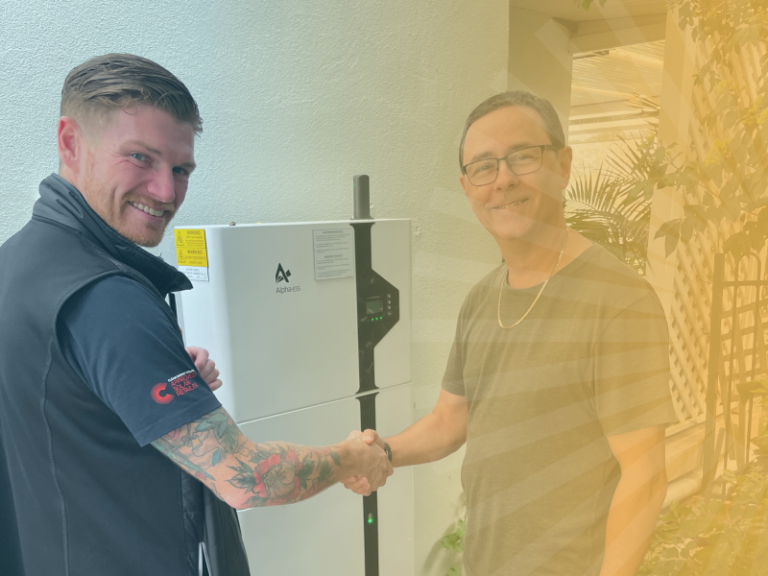 A worker shaking hands with a customer beside a new battery