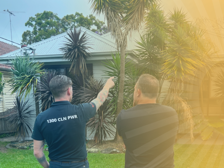 A worker pointing up at a house roof while a customer looks on