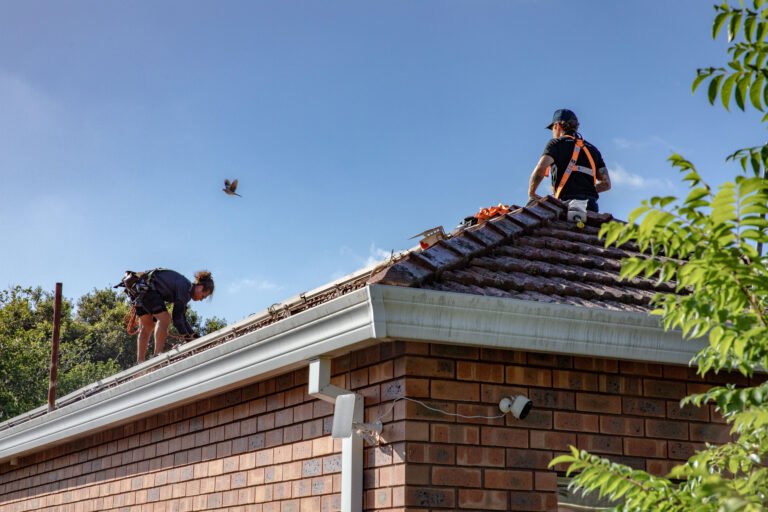Two installers working at the ridge of a tiled roof
