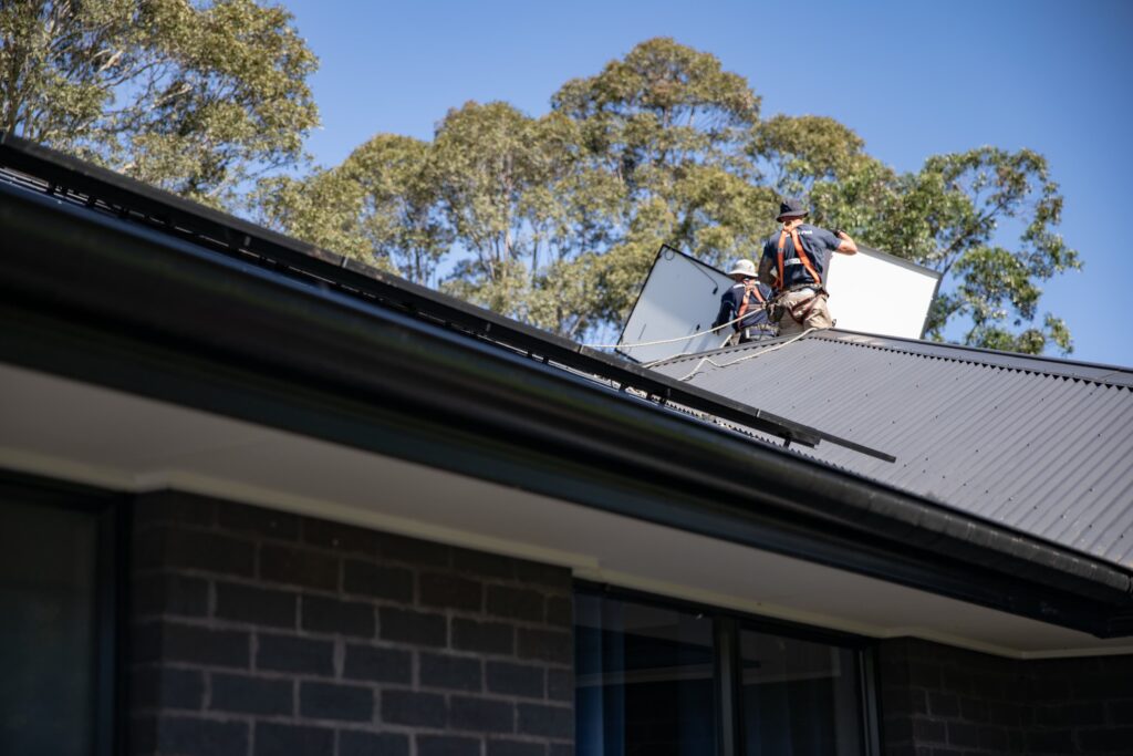 An installer lifting a panel onto the roof, the Mid North Coast