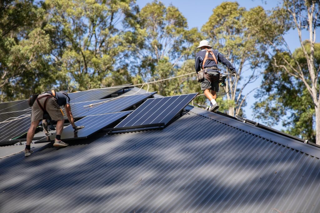 Two installers fixing panels on a pitched metal roof, Wollongong & the Illawarra