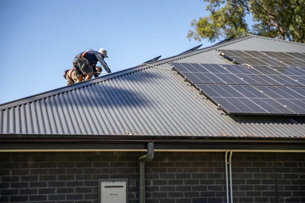 An installer kneeling to fix panels into place, the Northern Rivers & Tweed