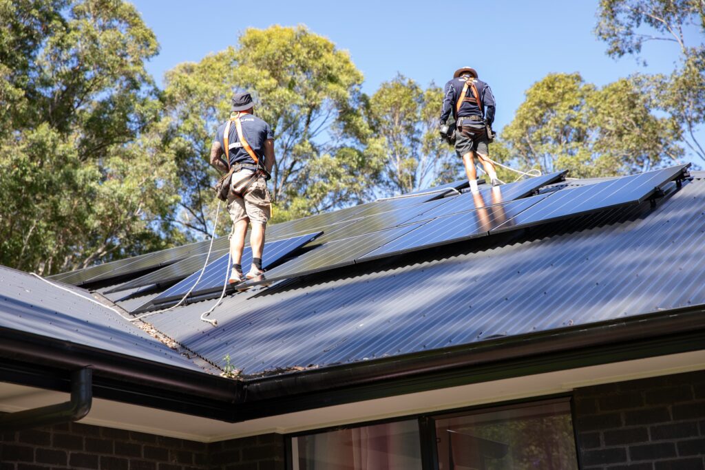 Two installers in harnesses on a completed array, the Central Coast