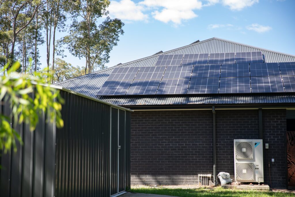 A roof full of solar panels above a brick wall and air conditioner