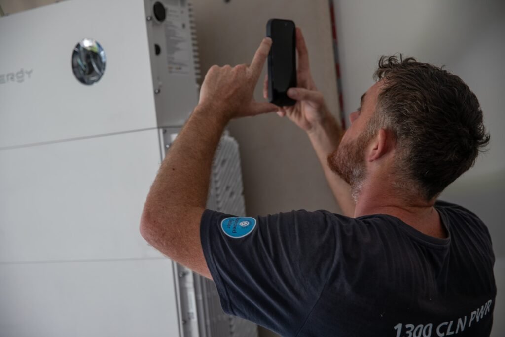 An installer beside a floor-standing home battery, Adelaide