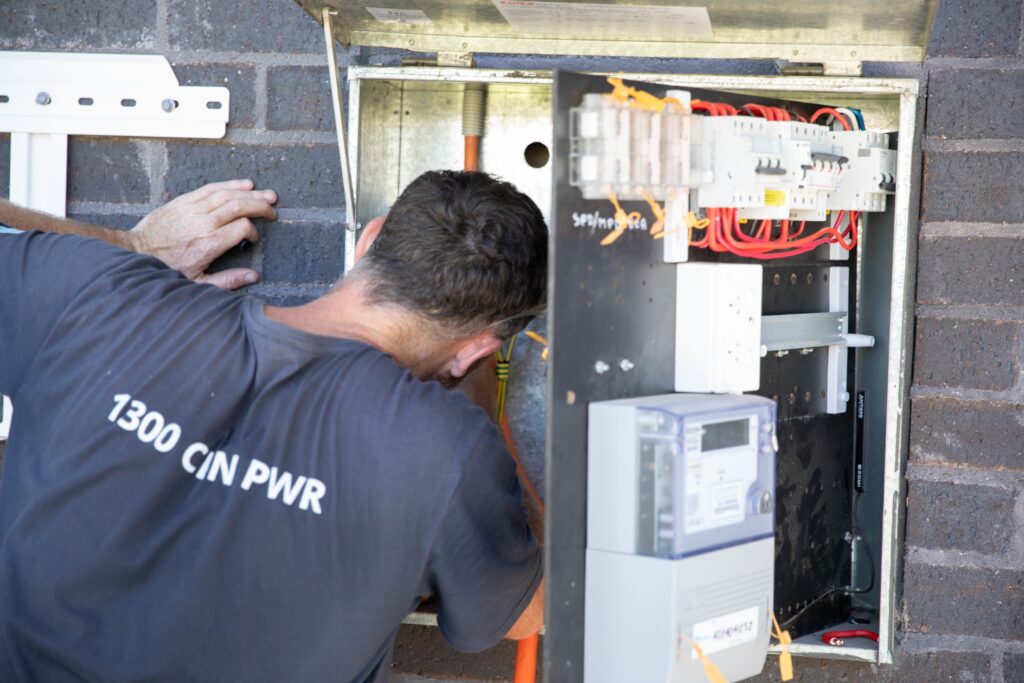 An installer wiring an open switchboard, the Central Coast