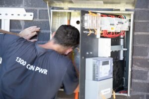 An electrician working inside an open meter box