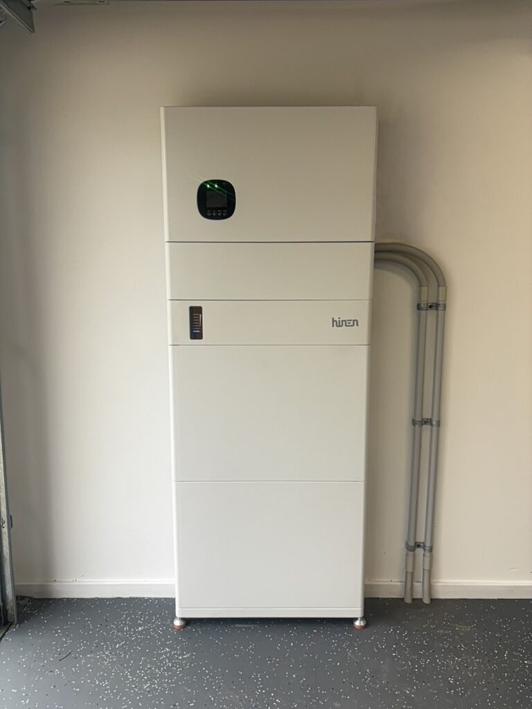A stacked home battery system installed in a garage, with conduit running to the wall