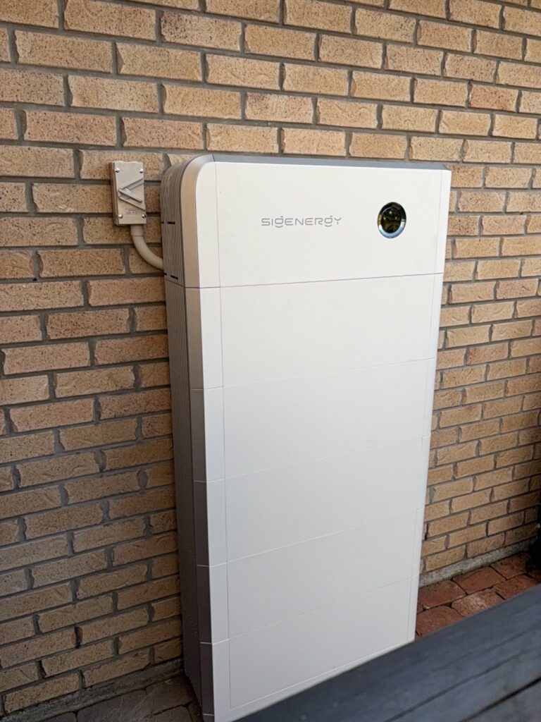 A Sigenergy home battery installed outdoors against a brick wall